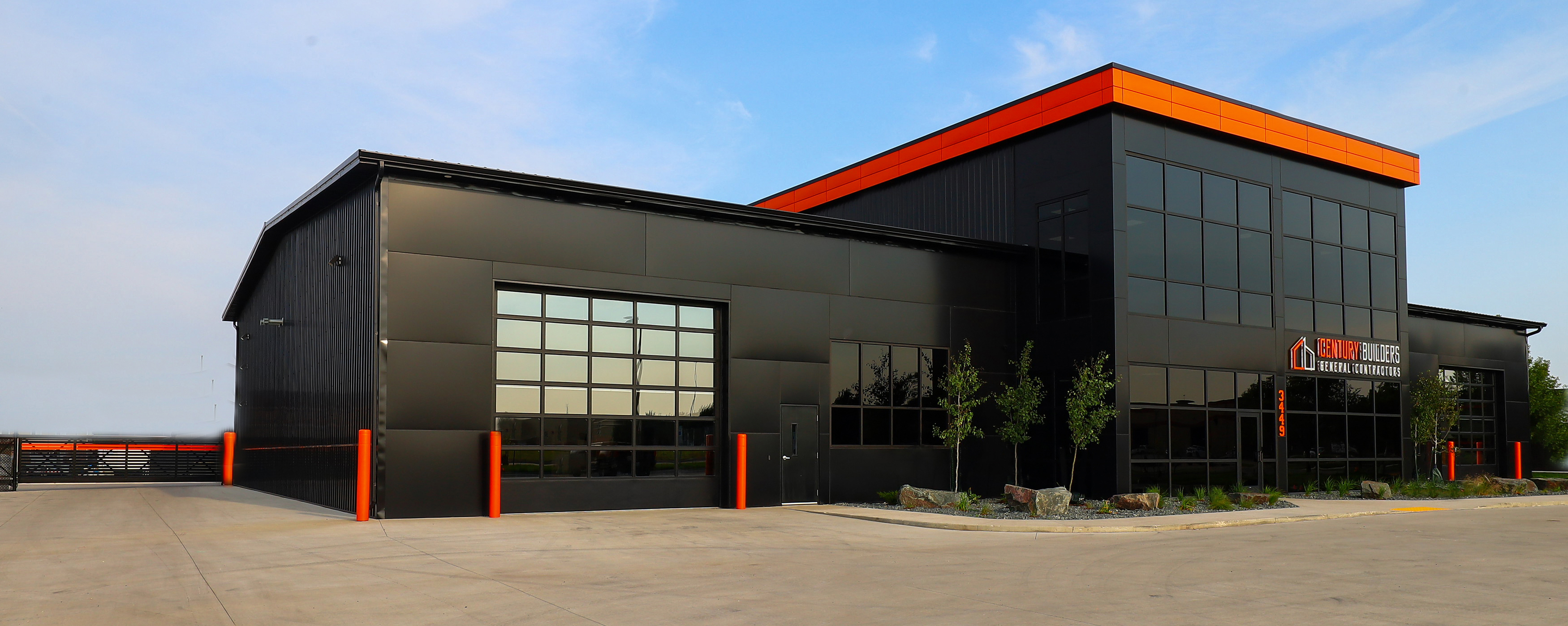 Century Builders Fargo office and shop building with dark metal siding and orange trim