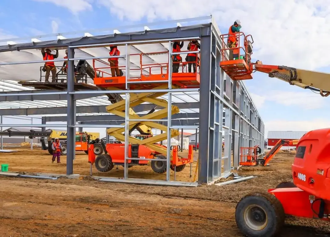 Steel building frame under construction with crews on lifts